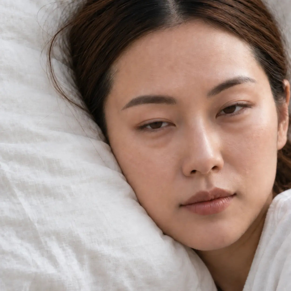 Femme au réveil, paupières lourdes et poches sous les yeux, avant l'application du Gel Anti-Poches Glimoir