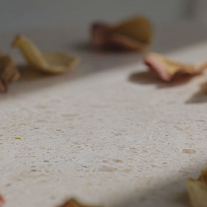 Texture de la Crème Apaisante Glimoir, ruban de crème onctueuse qui s'enroule en spirale sur la pierre travertine