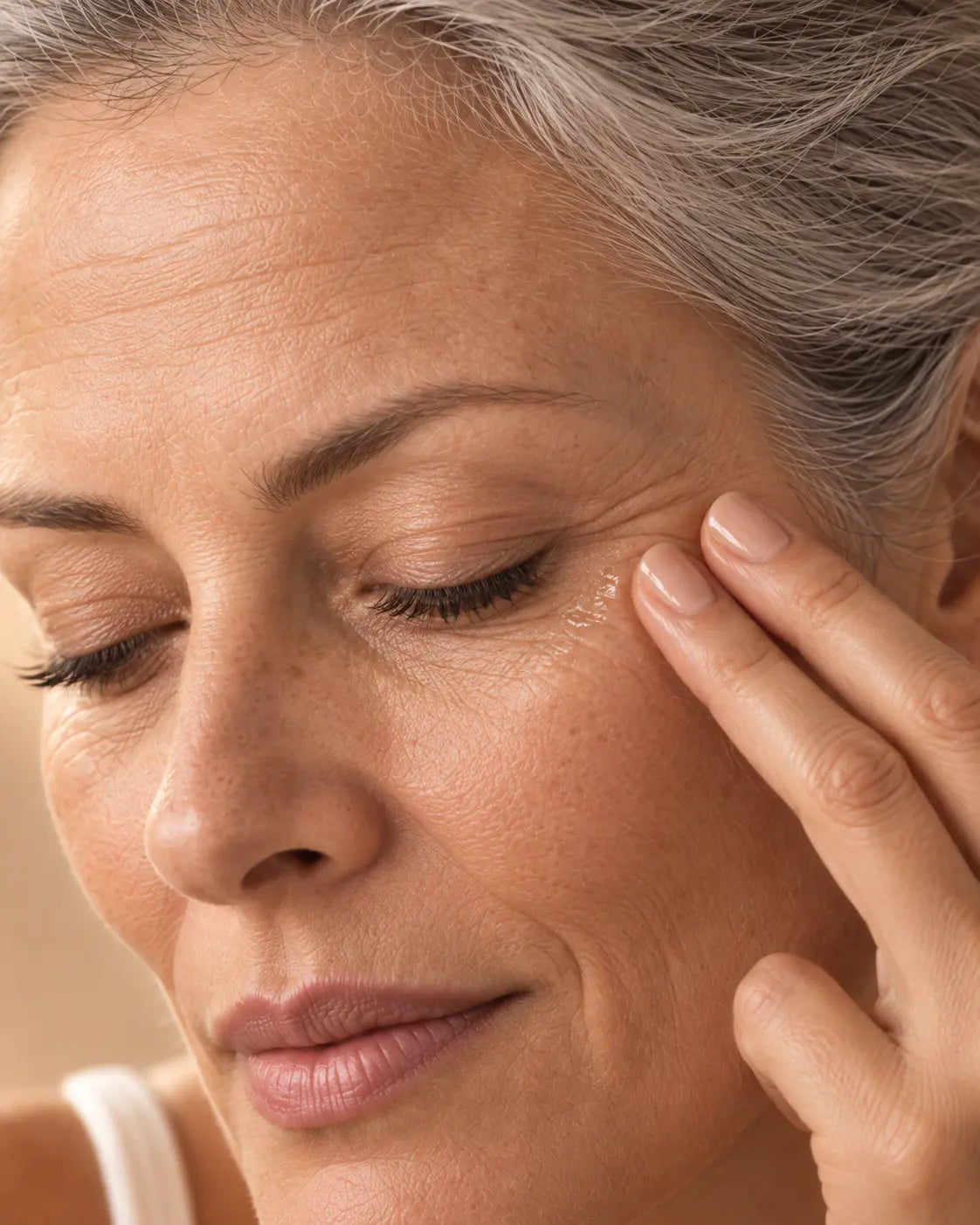 Femme appliquant un soin anti-rides sur le contour des yeux, routine Anti-Âge Glimoir