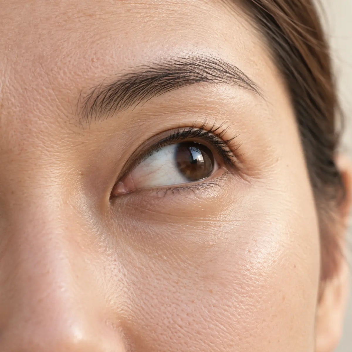 Gros plan sur le contour de l'œil après application du Sérum Exosomes Glimoir, peau lumineuse et texture naturelle